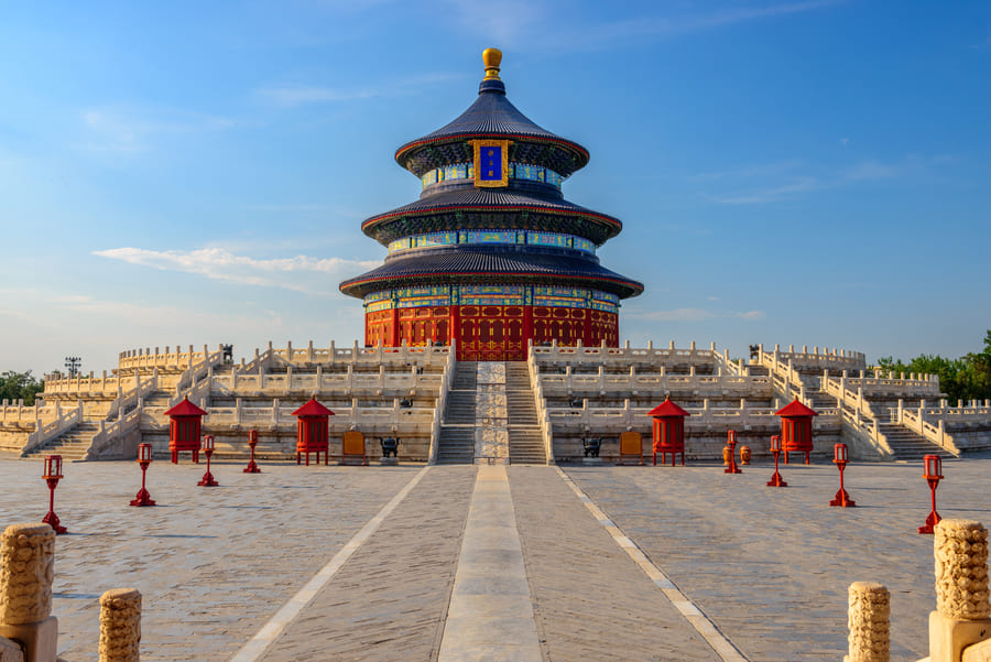 Vista frontal del Templo del Cielo en Beijing, destacando su icónica estructura circular de tres niveles con techo azul sobre una amplia plataforma de piedra bajo un cielo despejado.